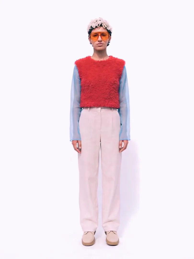 The LEVÉ character standing in the full Noon Uniform, red mohair vest and powder-blue mesh sleeves